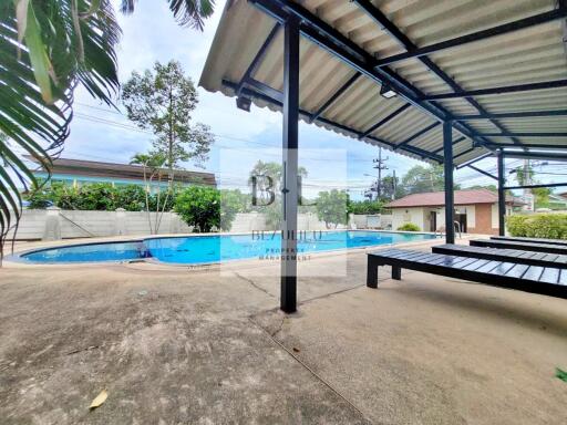 Covered patio area near swimming pool with seating