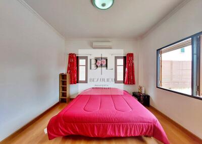 Spacious bedroom with red bedding and large windows