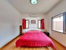 Spacious bedroom with red bedding and large windows