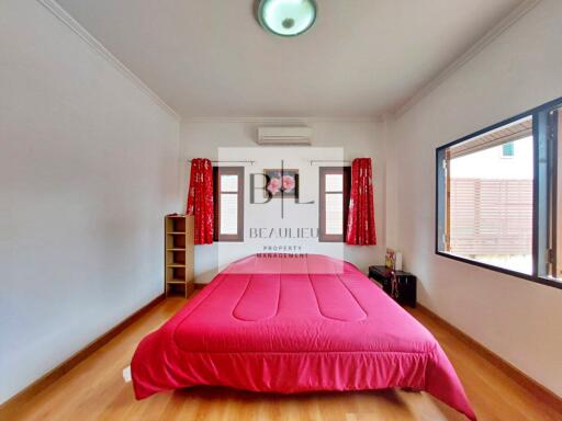 Spacious bedroom with red bedding and large windows