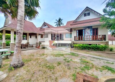 Exterior view of a large house with palm trees and garden