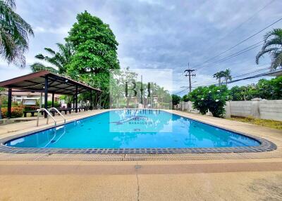 Outdoor swimming pool area with trees and a covered seating area