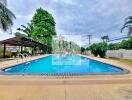 Outdoor swimming pool area with trees and a covered seating area