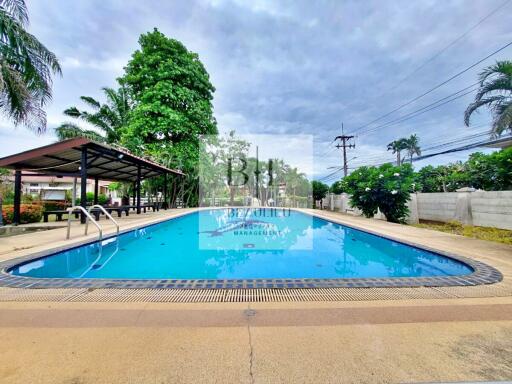 Outdoor swimming pool area with trees and a covered seating area