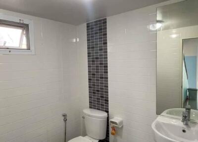 Modern bathroom with toilet, sink, and tiled walls