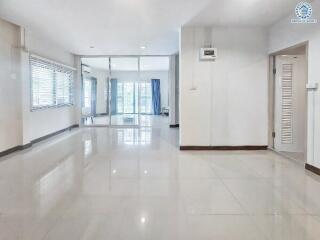 Spacious main living area with reflective floor tiles and large windows for natural light