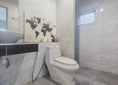 Modern bathroom with white marble walls and tiles, a toilet, and a sink with a mirror.