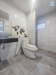 Modern bathroom with white marble walls and tiles, a toilet, and a sink with a mirror.