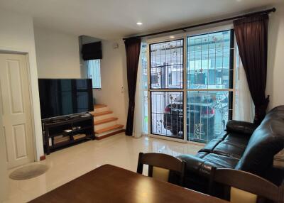 Living room with a large window, TV area, and staircase