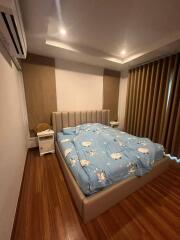 Bedroom with wooden floor, double bed, blue-themed bedding, and curtains