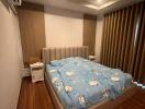 Bedroom with wooden floor, double bed, blue-themed bedding, and curtains