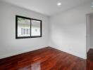 Empty bedroom with wooden floor and a large window