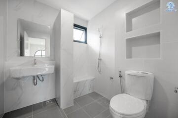 Modern bathroom with gray tiles, wall-mounted sink, toilet, and walk-in shower