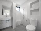 Modern bathroom with gray tiles, wall-mounted sink, toilet, and walk-in shower