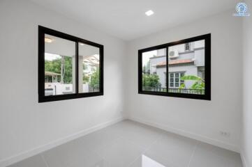 A bright bedroom with large windows and tile flooring