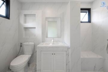 Modern white bathroom with built-in shelving, toilet, and sink