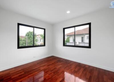 Empty bedroom with wooden floor and large windows