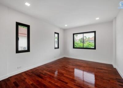 Spacious bedroom with wooden floors and large windows