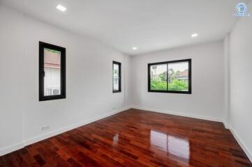 Spacious bedroom with wooden floors and large windows