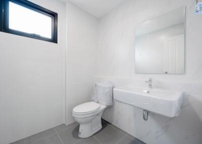 Minimalistic white bathroom with a window, toilet, and wall-mounted sink