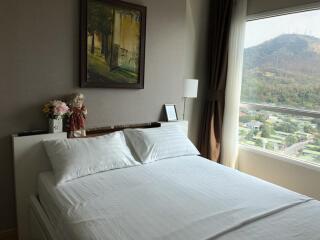 Bright bedroom with a large window, white bedding, and wall art