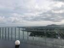 Balcony with glass railing overlooking a scenic landscape with mountains and a body of water