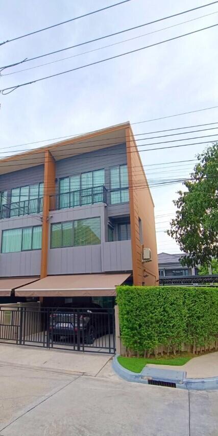 Modern three-story townhouse with a garage and green hedges