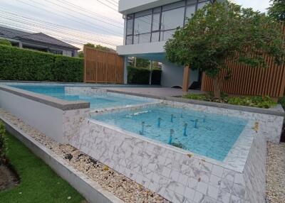 Modern outdoor pool area with a two-level pool and greenery