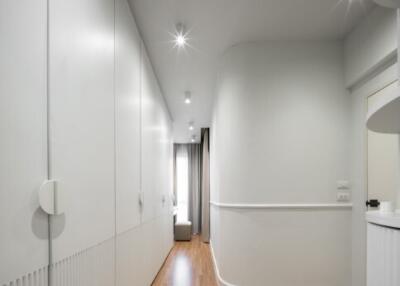 Well-lit modern hallway with wooden floors and white walls