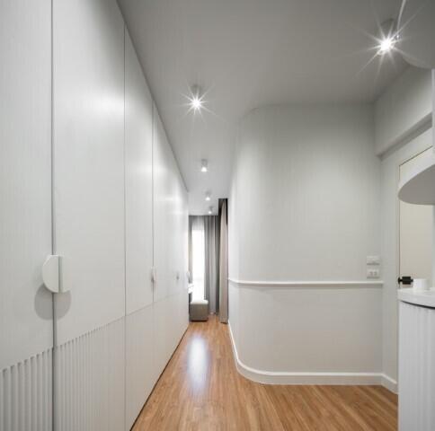 Well-lit modern hallway with wooden floors and white walls