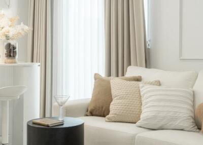 Living room with neutral decor featuring a white couch and beige curtains