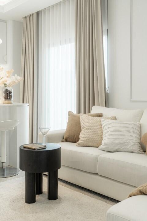 Living room with neutral decor featuring a white couch and beige curtains