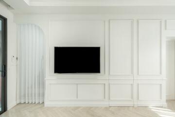 Minimalist living room with white paneled walls and wall-mounted TV