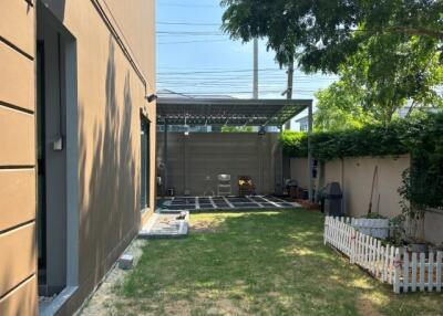 A modern backyard with green lawn and seating area under a canopy