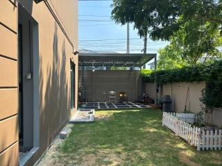 A modern backyard with green lawn and seating area under a canopy