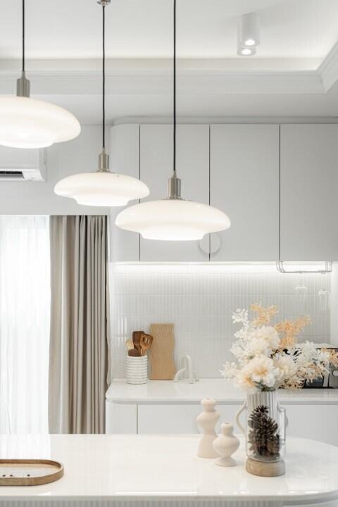 Modern kitchen with white cabinetry, pendant lights, and elegant decor