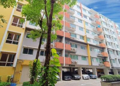 Exterior view of an apartment building with multiple floors and a parking area