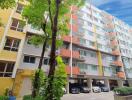 Exterior view of an apartment building with multiple floors and a parking area