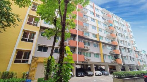 Exterior view of an apartment building with multiple floors and a parking area