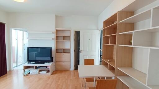 Living room with wooden bookshelves, TV and dining area