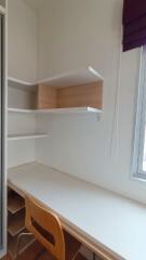 A study area with a desk, chair, shelving and a window