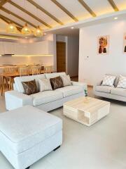 Modern living room with wooden beams, contemporary furniture, and open kitchen