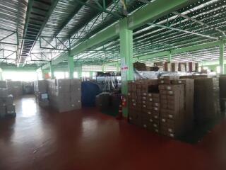 Spacious warehouse with green pillars and stacked boxes