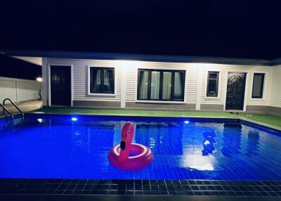 Backyard swimming pool at night with a house in the background