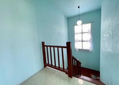 Staircase with wooden railings and a small window