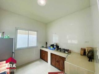 Clean, white-tiled kitchen with window, countertops, and modern appliances