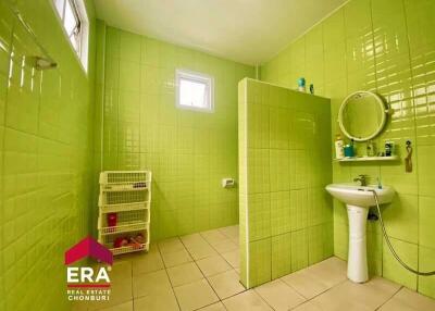 Spacious bathroom with green tiles, white fixtures, and a small storage unit