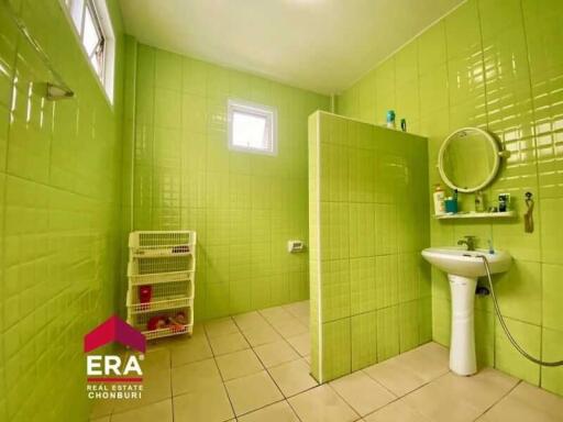 Spacious bathroom with green tiles, white fixtures, and a small storage unit