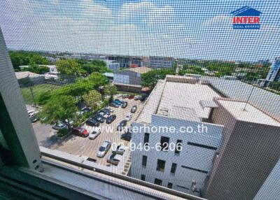 View of surrounding buildings and street from a window with a screen