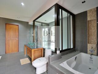 Modern bathroom with bathtub, glass shower, and wooden door